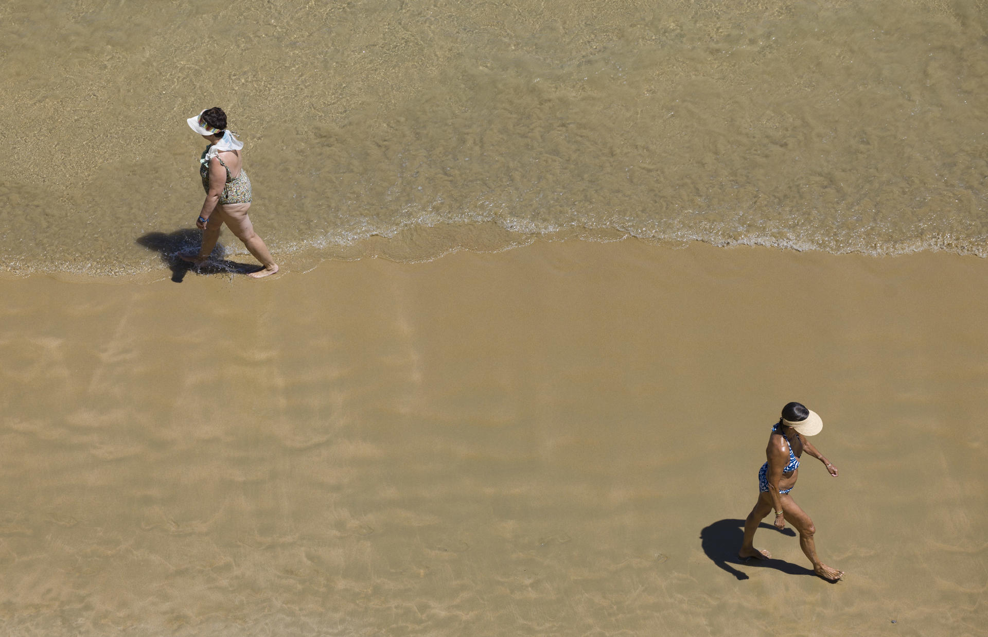 Dos mujeres pasean por la orilla de la playa de La Concha de San Sebastián este miércoles. EFE/Javier Etxezarreta