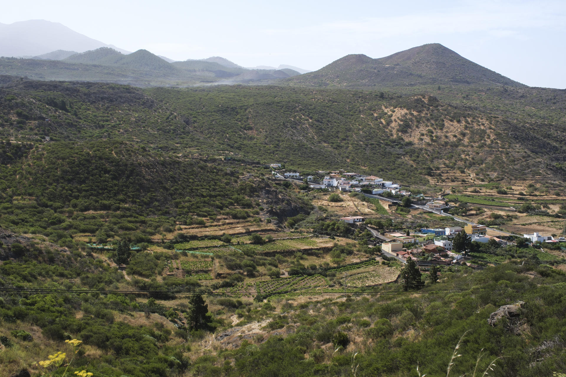 El Cabildo de Tenerife ha desplegado un contingente de 80 personas desde primera hora con nueve medios aéreos para extinguir el incendio declarado el martes en Los Partidos de Franquis, en El Tanque, y que también ha afectado a Santiago del Teide. En la imagen, el caserío de Villa de Arriba, en el municipio de Santiago del Teide, cuyos vecinos fueron desalojados durante buena parte del lunes por la amenaza que representaba el fuego. EFE/Alberto Valdés