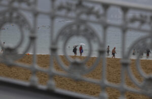 Una pareja se protege de la lluvia con paraguas este miércoles en la playa de la Concha de San Sebastián. EFE/Juan Herrero
