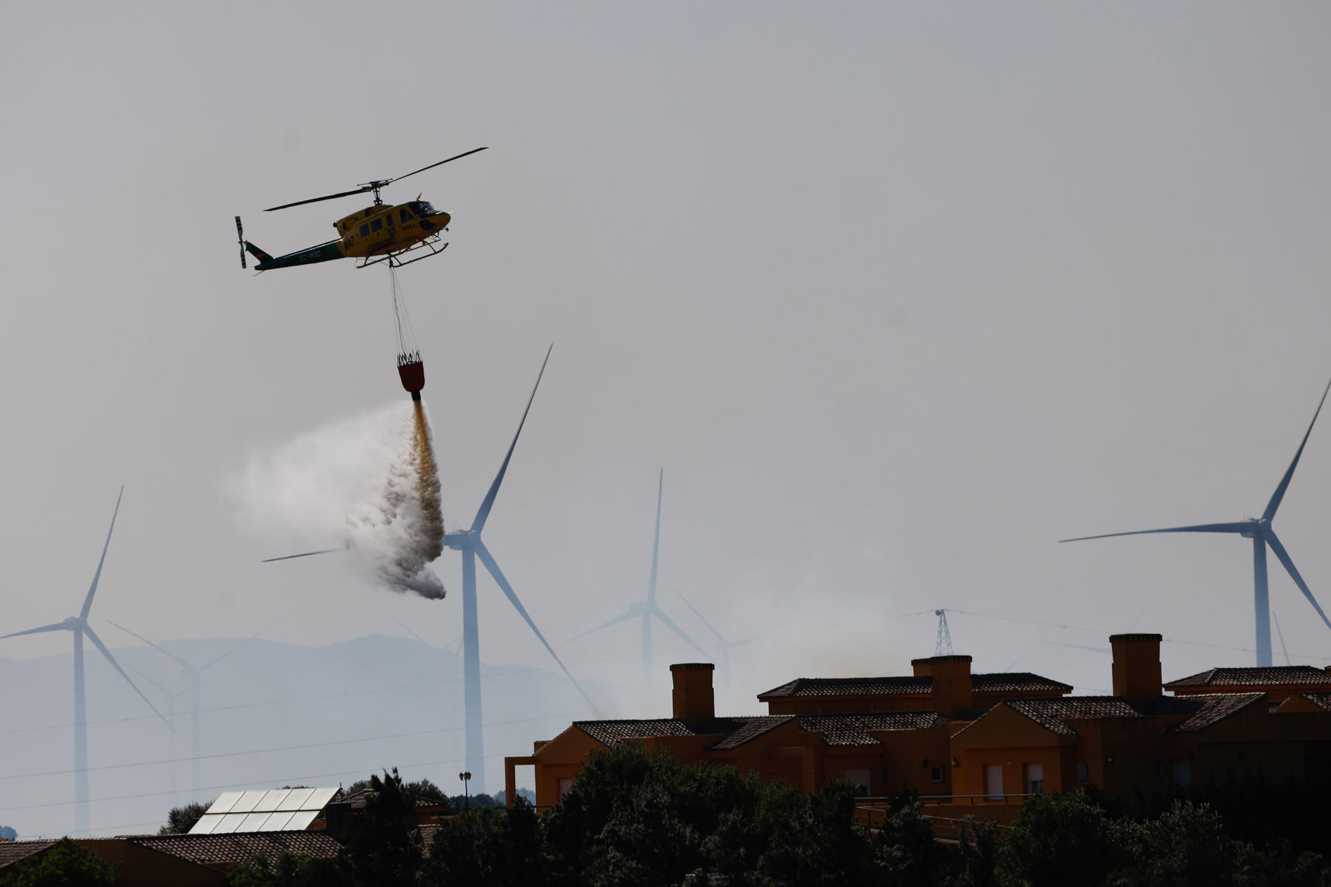 Un helicóptero intenta sofocar las llamas del incendio que se ha producido en el paraje de El Pedregoso, iniciado en un aerogenerador, en la localidad de Facinas (Tarifa). EFE/A.Carrasco Ragel.
