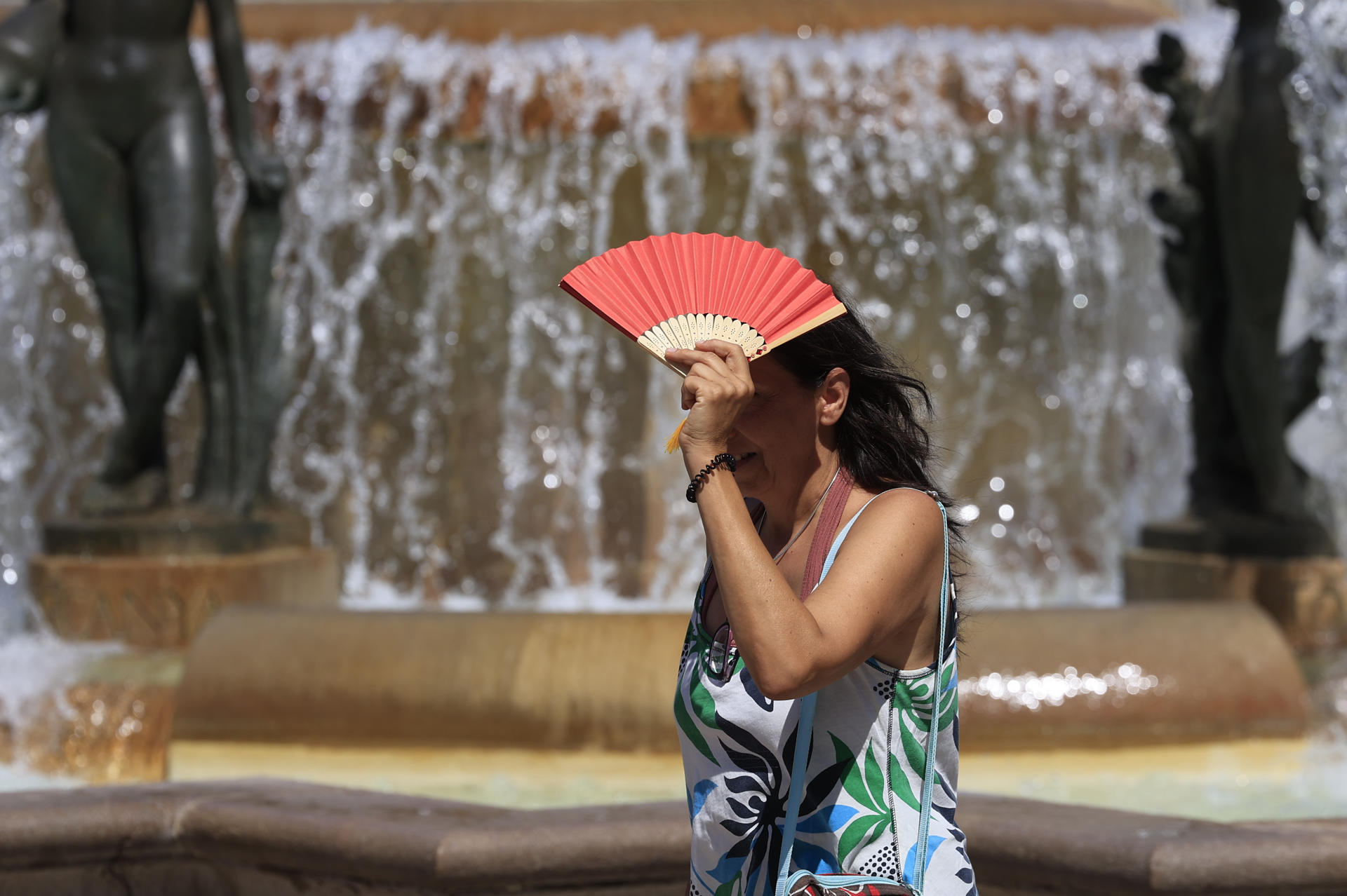 Una mujer se tapa del sol con un abanico este domingo en Valencia. La Agencia Estatal de Meteorología mantiene para hoy los avisos por probabilidad de chubascos y tormentas localmente fuertes en el interior de Valencia y Castellón, y se mantienen las temperaturas significativamente altas en el prelitoral de Valencia y del sur de Alicante. EFE/ Kai Forsterling
