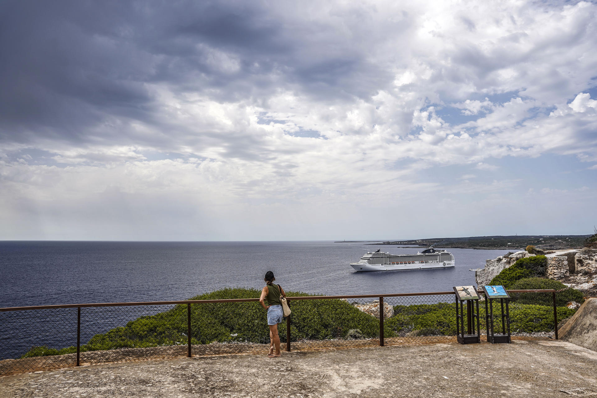 Turistas observan este miércoles la llegada de nubes de lluvia desde la Fortaleza de Isabel II en La Mola, Menorca. EFE/David Arquimbau Sintes