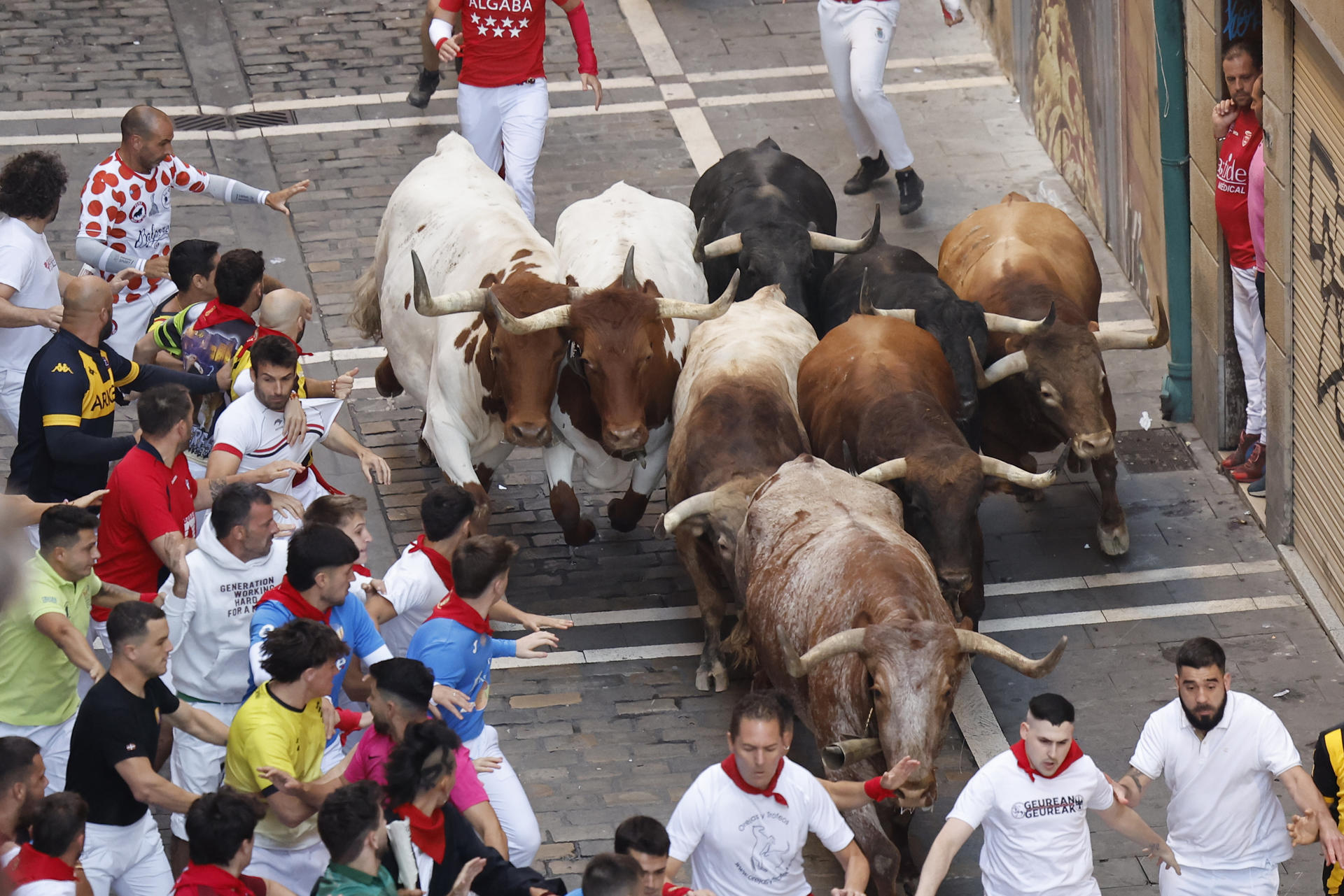 Los mozos son perseguidos por los toros de la ganadería Victoriano del Río Cortés durante el cuarto encierro de los Sanfermines, este jueves, en Pamplona. EFE/Villar López