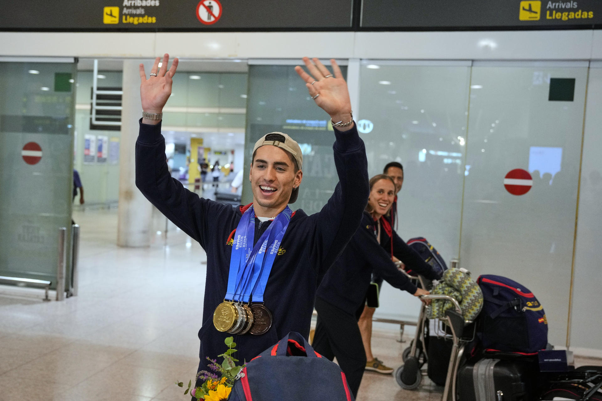 El nadador Dennis González saluda a su llegada al aeropuerto de El Prat. EFE/ Alejandro García
