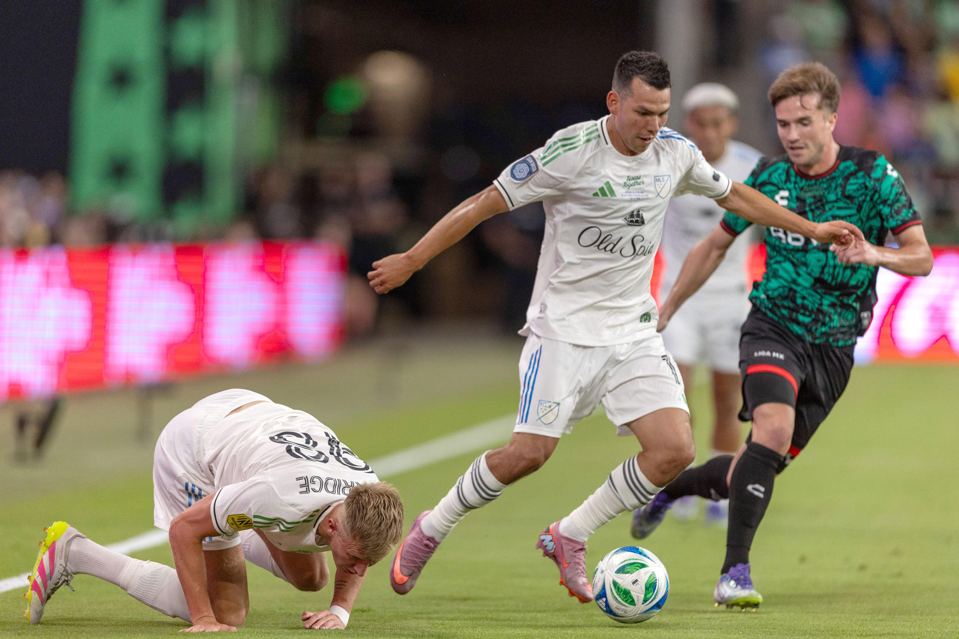 El delantero Hirving Lozano (c), de la selección de la MLS, lidera un ataque ante la marca de Agustín Palavecino rumbo a la portería del equipo de estrellas de la Liga MX durante el partido jugado este miércoles en en el estadio Q2 de Austin (Texas). EFE/ Carlos Ramírez
