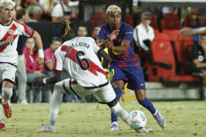 El centrocampista del Rayo Vallecano Pathé Ciss (i) lucha con Lamine Yamal, del FC Barcelona, durante el partido de la tercera jornada de LaLiga entre el Rayo Vallecano y el FC Barcelona, este domingo en el estadio de Vallecas. EFE/Chema Moya