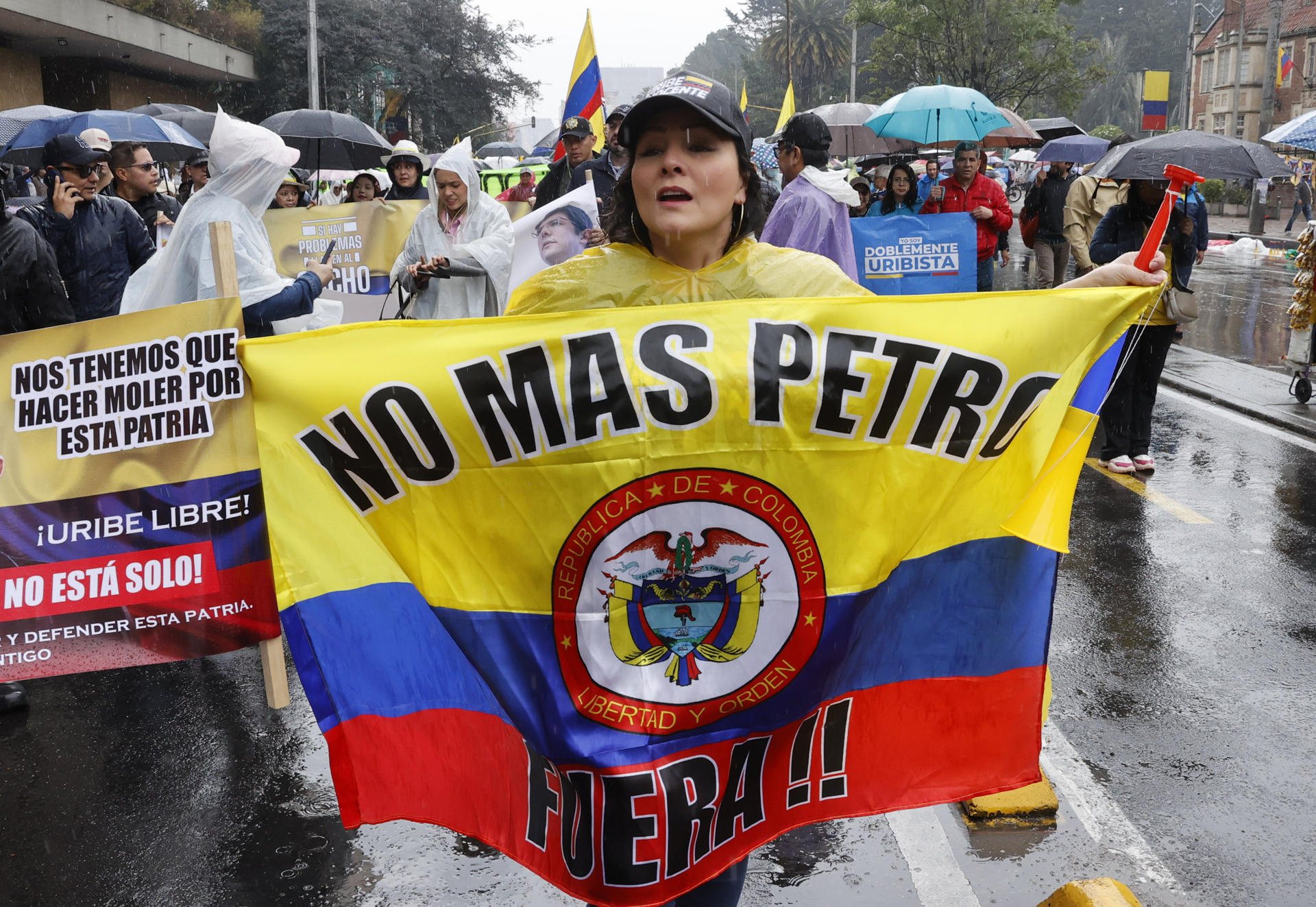 Una seguidora del expresidente colombiano Álvaro Uribe sostiene una bandera bajo la lluvia este jueves, en Bogotá (Colombia). EFE/ Mauricio Dueñas Castañeda
