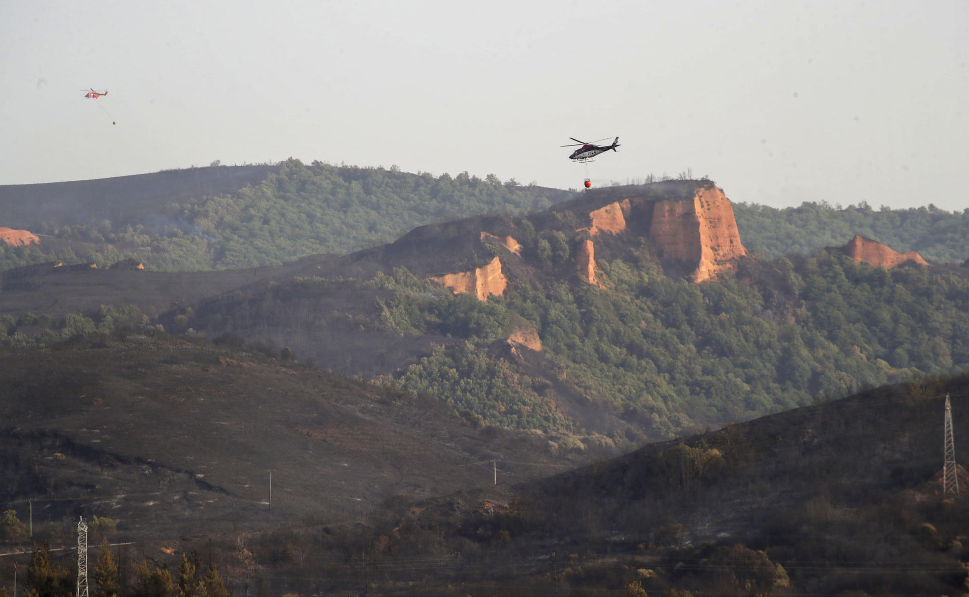 Medios aéreos sobre una zona afectada por el fuego que ha arrasado parte del espacio natural de Las Médulas, catalogado por la Unesco como Patrimonio de la Humanidad y corazón turístico de la comarca leonesa de El Bierzo, que ha dejado una sensación entre los vecinos de vivir un infierno del que tardarán años en salir. EFE/Ana F. Barredo