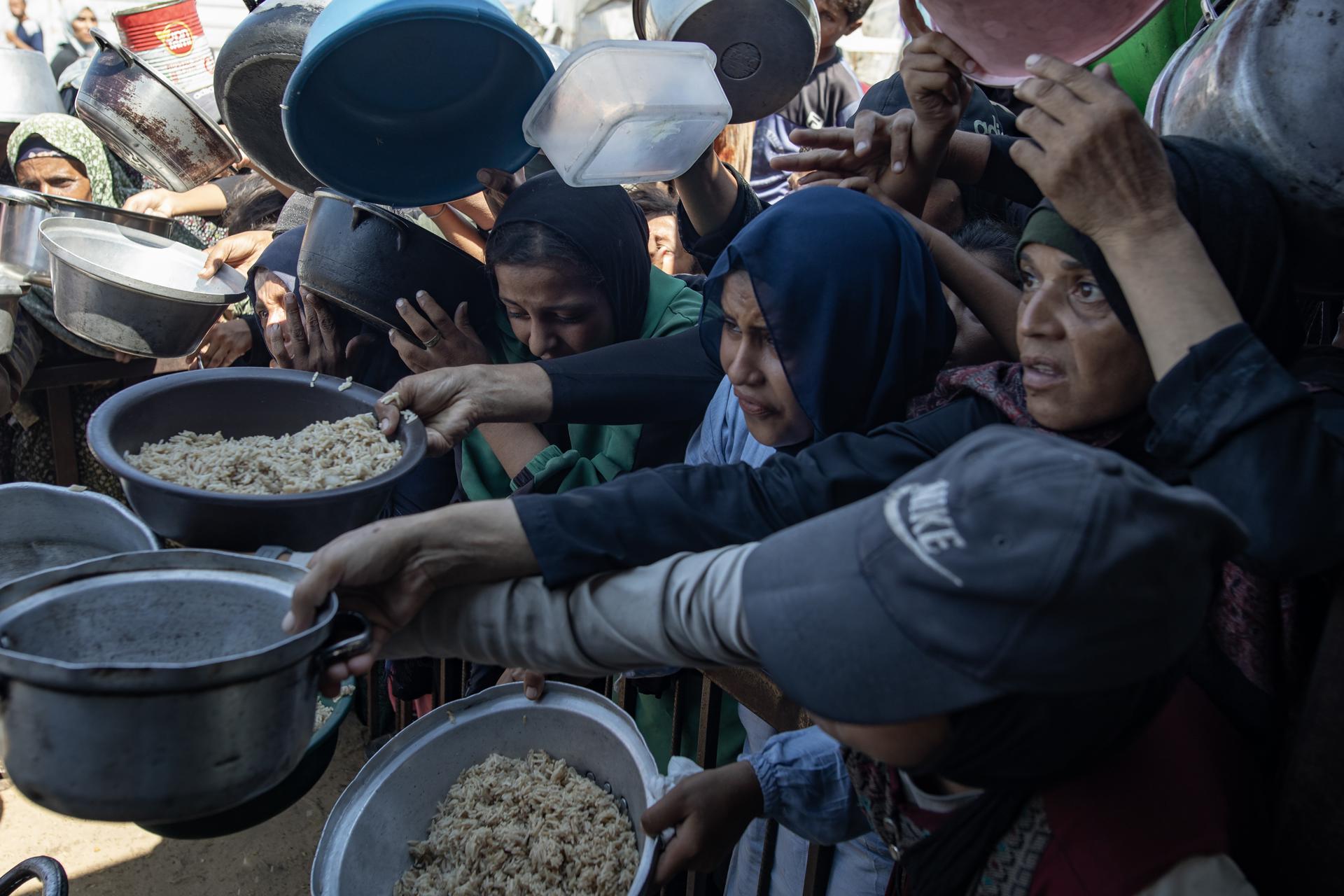 Los palestinos hacen cola para recibir una comida de una cocina que proporciona alimentos gratuitos para las personas desplazadas en Khan Yunis, en la Franja de Gaza sur, el 23 de agosto de 2025. EFE/EPA/HAITHAM IMAD
