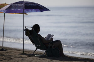 Una mujer lee bajo la sombra de una sombrilla en la playa del Rincón de la Victoria (Málaga), este miércole. EFE/Jorge Zapata
