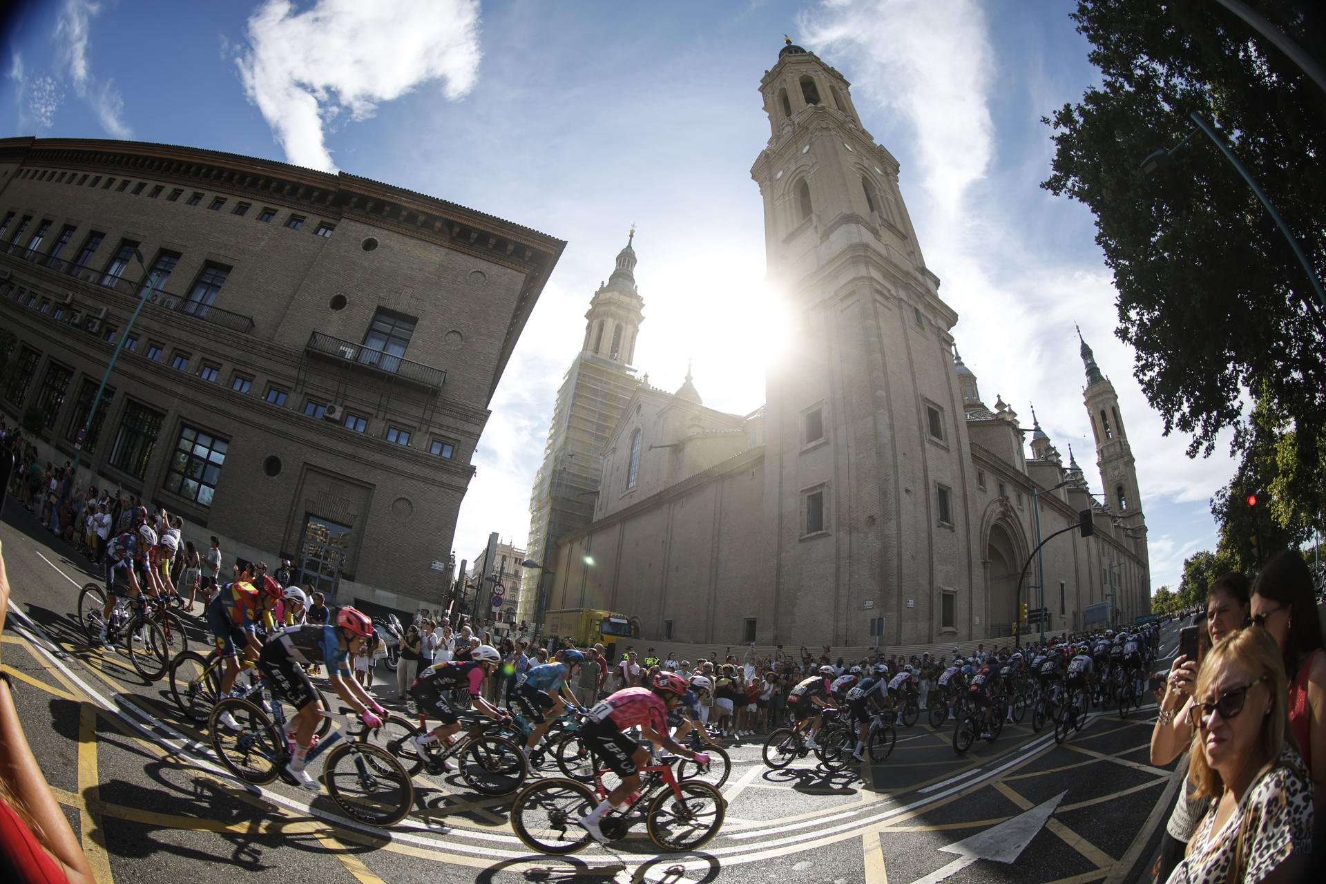 El pelotón circula junto a la Basílica del Pilar durante la octava etapa de la Vuelta a España, este sábado entre Monzón (Huesca) y Zaragoza, en un recorrido de 163,5 kilómetros. EFE/Javier Lizón