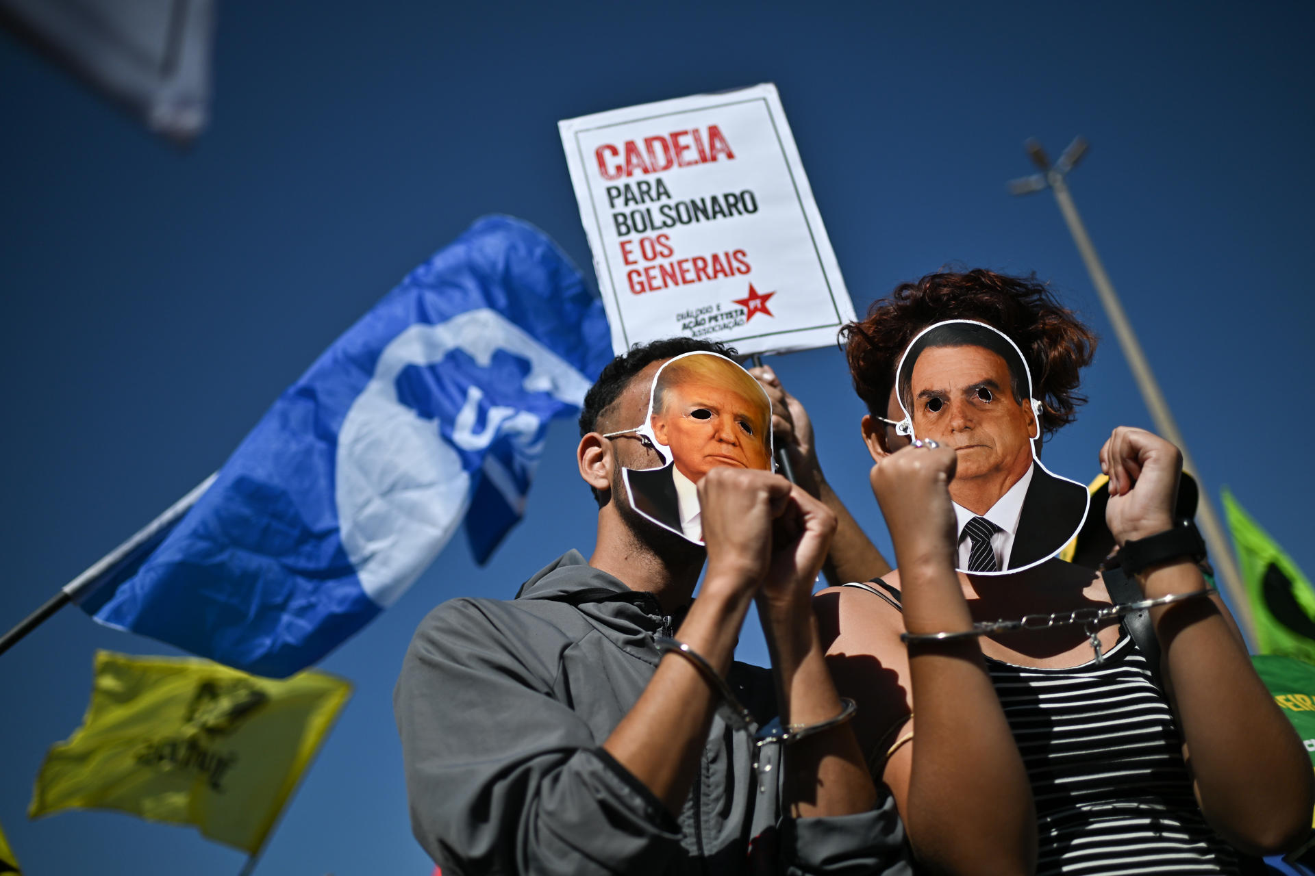 Personas usan esposas y máscaras con la imagen del presidente de Estados Unidos, Donald Trump, y del expresidente de Brasil, Jair Bolsonaro, durante una protesta en defensa de la soberanía nacional y contra los aranceles estadounidenses este 1 de agosto de 2025 frente de la Embajada de los Estados Unidos en Brasilia (Brasil). EFE/ Andre Borges