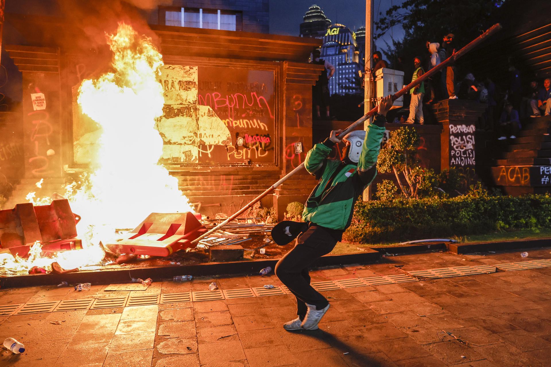 Un manifestante fue captado este viernes, 29 de agosto, al quemar barreras viales, durante una protesta frente a la sede de la policía de Yakarta, en la capital de Indonesia. EFE/Mast Irham