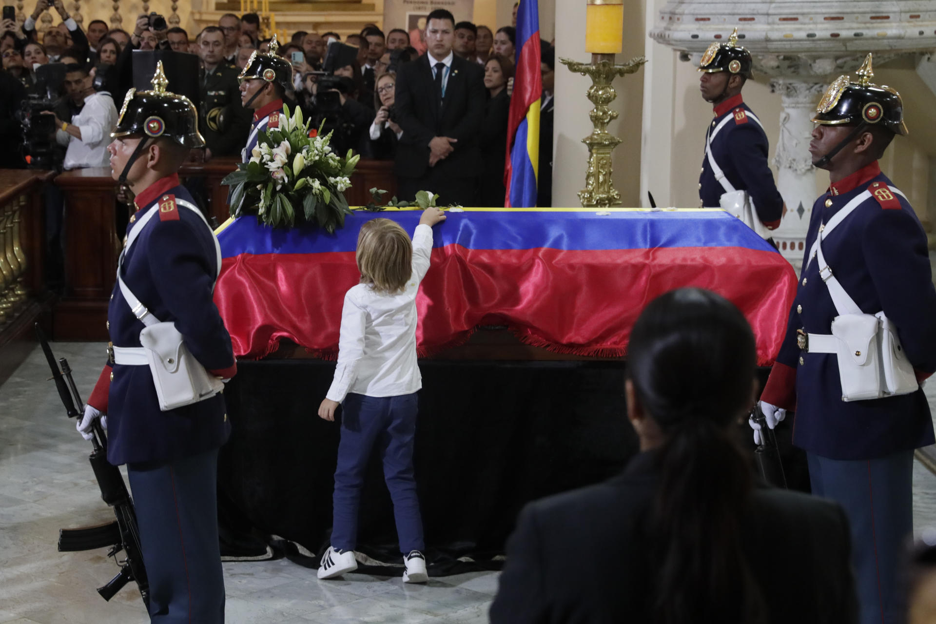 El hijo del fallecido senador y precandidato presidencial Miguel Uribe Turbay, Alejandro (c-i), fue captado este miércoles, 13 de agosto, al dejar una flor sobre el féretro de su padre, durante las exequias en la catedral Primada, en Bogotá (Colombia). EFE/Carlos Ortega