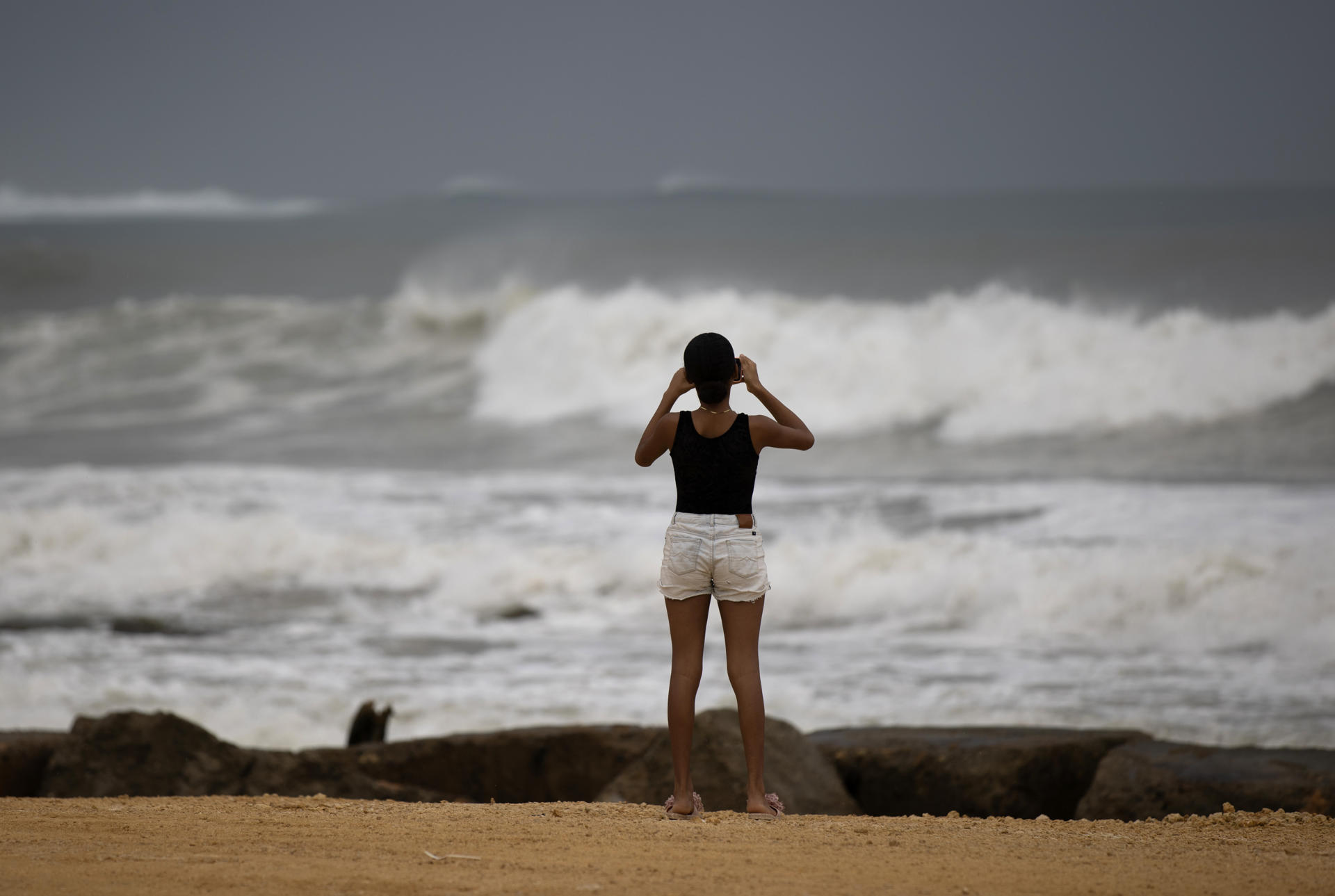 Una persona toma una fotografía al mar este domingo, en Nagua (República Dominicana). EFE/ Orlando Barría