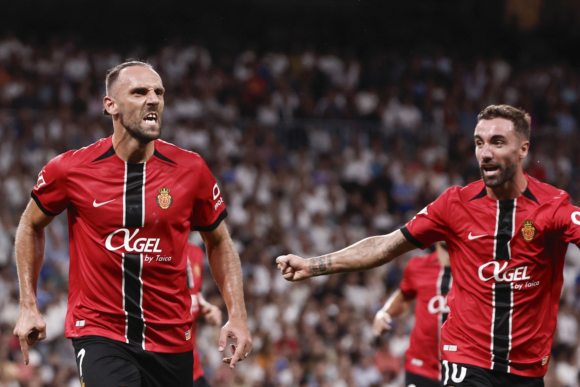 El delantero kosovar del Mallorca Vedat Muriqi (i) celebra su gol durante el partido de la tercera jornada de LaLiga entre el Real Madrid y el RCD Mallorca, este sábado en el estadio Santiago Bernabéu. EFE/Sergio Pérez