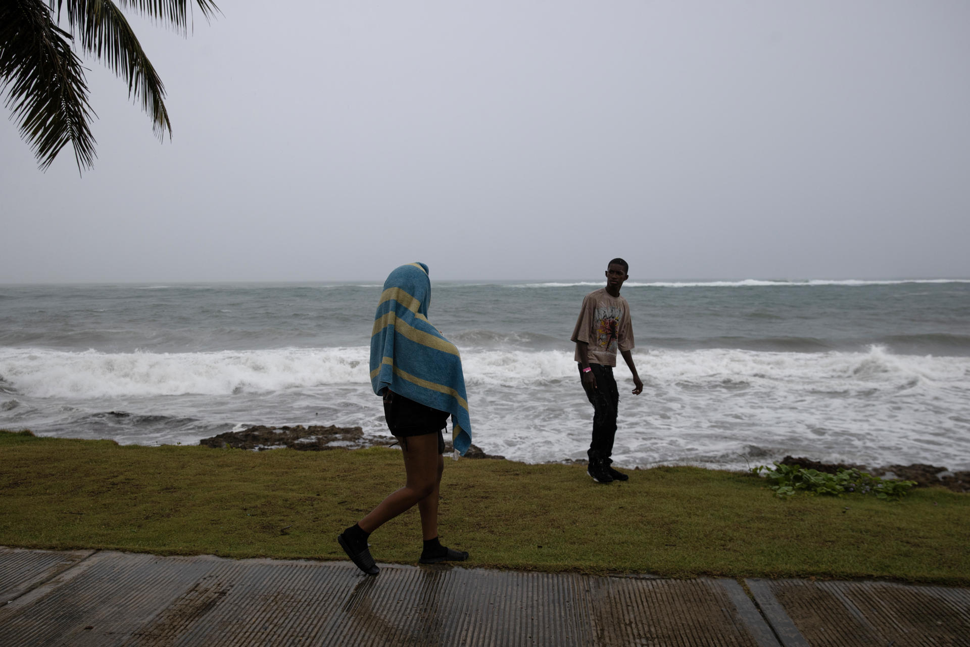Personas caminan frente al mar este domingo, en Nagua (República Dominicana). EFE/ Orlando Barría