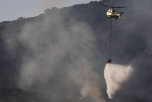Un helicóptero trabaja en las labores de extinción del incendio que desde ayer afecta a la Sierra de la Plata, en Tarifa (Cádiz), y que sigue activo y mantiene a unas 900 personas desalojadas de sus casas y hoteles. Cuatro medios aéreos se incorporan la mañana de este martes a dichas tareas. EFE/Román Ríos