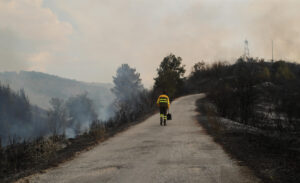 Un voluntario y profesionales se enfrentan a las llamas de un incendio en Molinaseca (Ponferrada), en una imagen de este domingo. EFE/ Ana F. Barredo