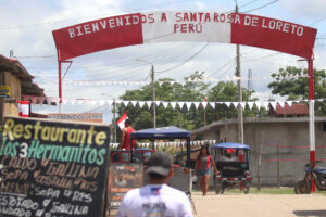 Personas se movilizan en una calle que muestra un letrero fronterizo este miércoles, en la población de Santa Rosa, una isla en medio del río Amazonas bajo soberanía peruana, situada frente a la ciudad colombiana de Leticia, en la triple frontera amazónica con Brasil. EFE/ Stringer