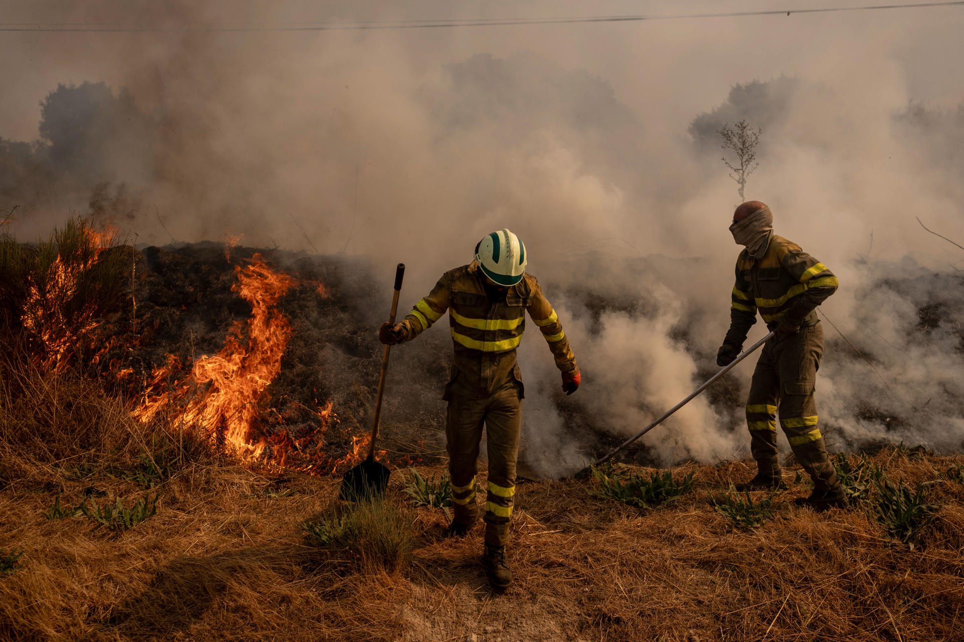 Dos voluntarios realizan labores de extinción en el incendio de Oímbra (Ourense) este martes. EFE/ Brais Lorenzo
