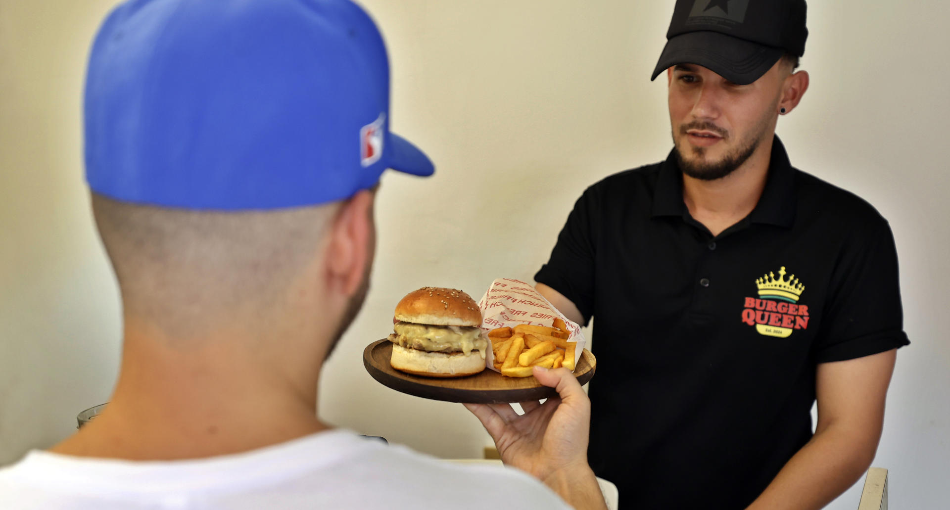 Fotografía del 2 de agosto de 2025 de un trabajador de la cafetería Burguer Queen atendiendo a una persona, en La Habana (Cuba). EFE/ Ernesto Mastrascusa