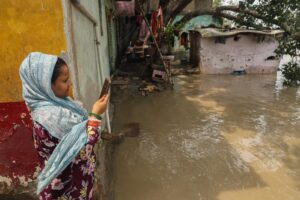 Una mujer toma una fotografía cerca de su casa afectada por las lluvias en Nueva Delhi, la India. EFE/EPA/RAJAT GUPTA