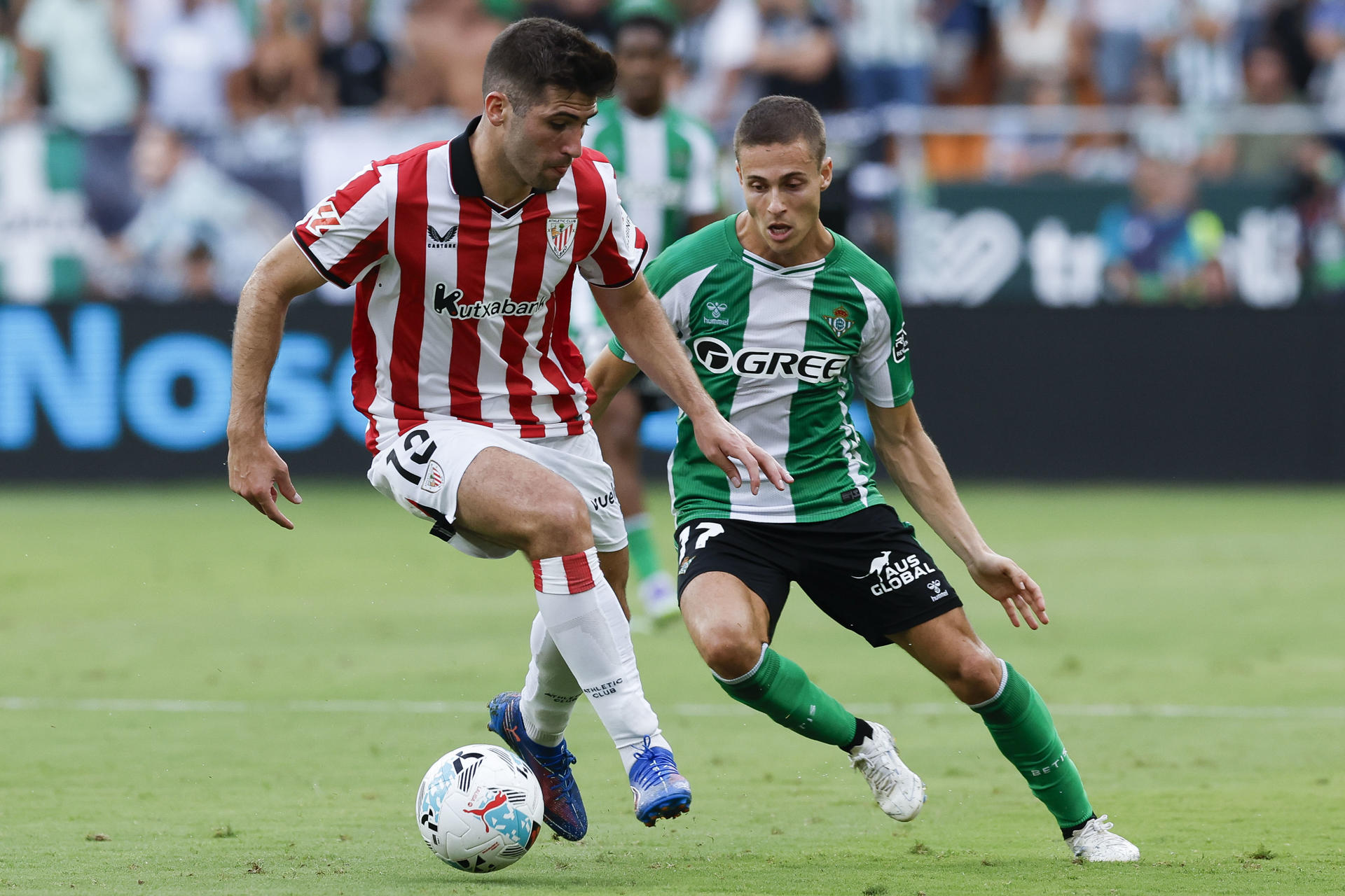 El defensa del Athletic Jesús Areso (i) pelea un balón con el centrocampista del Betis Rodrigo Riquelme durante el partido de LaLiga entre el Betis y el Athletic Club, este domingo en el estadio de la Cartuja. EFE/ Julio Muñoz