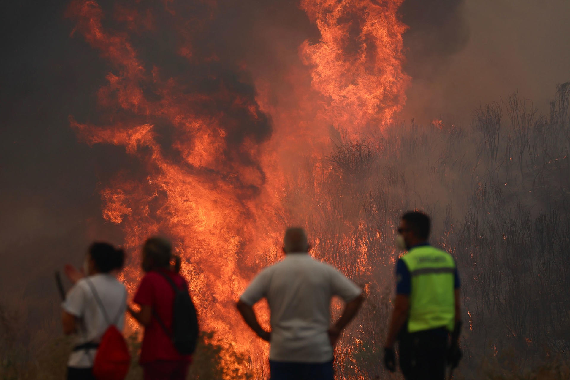 Varias personas luchan contra las llamas del incendio de A Gudiña (Ourense), este jueves. La DGT ha informado de que la circulación en la autovía A-52 está cortada entre los kilómetros 124 y 129 por los incendios forestales, concretamente en la zona de A Gudiña. La autovía está cortada en ese tramo en ambos sentidos y también está afectada la N-525 en los puntos kilométricos 129 y 86. EFE/ Sxenick

