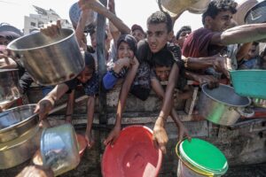 Palestinos desplazados internamente, incluidos niños, sostienen ollas mientras se reúnen para recibir alimentos de una cocina de caridad, en la Franja de Gaza, en una fotografía del 04 de agosto de 2025. EFE/MOHAMMED SABER