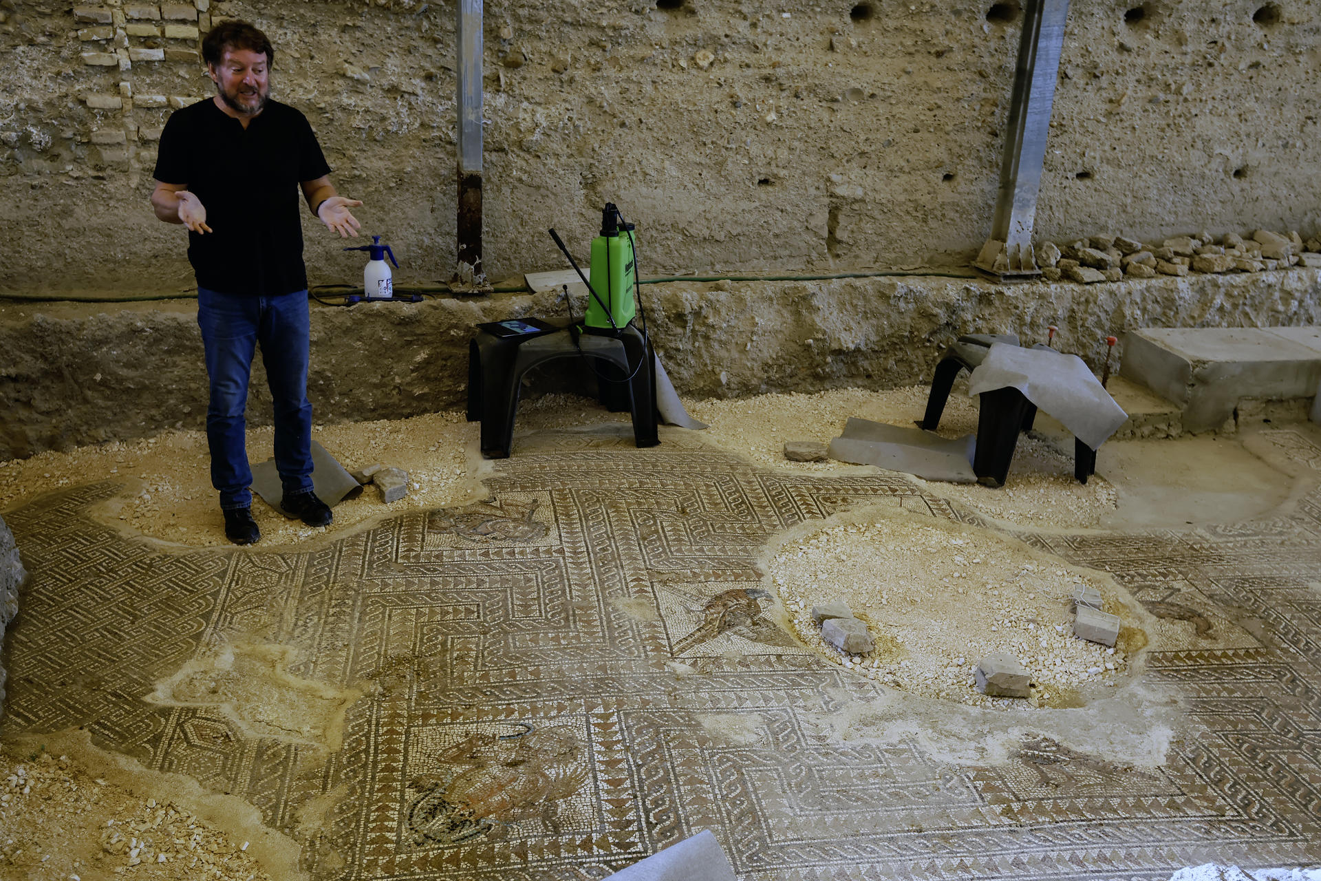 El arqueólogo municipal de Écija (Sevilla), Sergio García-Dils, junto al nuevo mosaico de 27 metros cuadrados hallado en el centro de esta ciudad, que corrobora, el lujo, la ostentación y la riqueza que disfrutaron las aristocracias locales romanas durante el siglo III, gracias al comercio del aceite de oliva. EFE/José Manuel Vidal