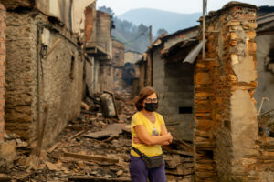 Una vecina entre las casas calcinadas de la aldea de San Vicente, este lunes en Vilamartín de Valdeorras (Ourense). EFE/ Brais Lorenzo