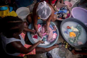 Fotografía de mujeres lavando ropa en el interior de una carpa en un campamento de refugiados, en Puerto Príncipe (Haití). EFE/ Mentor David Lorens