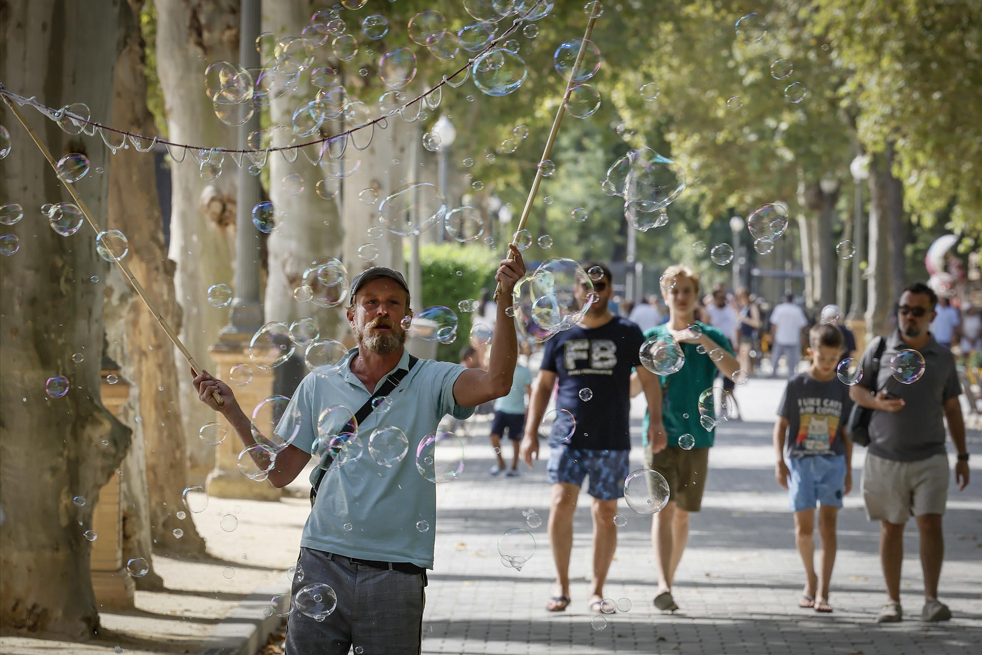 Un hombre hace pompas de jabón para los turistas este lunes de Sevilla, al inicio de la segunda ola de calor de este verano con temperaturas que superan los 40 grados. La persistencia de una masa de aire cálido procedente del norte de África, combinada con un bloqueo anticiclónico sobre la península, agravará la sensación térmica durante toda la semana. EFE /Jose Manuel Vidal