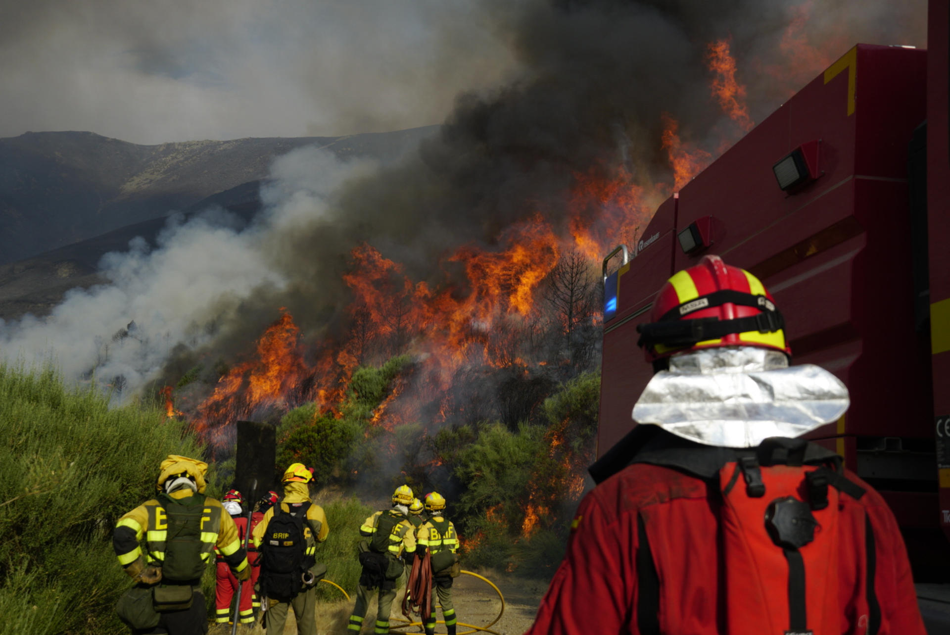 Vecinos de la zona esperan ordenes de La UME para bajar a refrescar la zona e impedir el avance del fuego hacia Santo tirso en la carretera desde Santo Tirso de Cabarcos a Oencia en Ponferrada, León, este lunes. Durante los últimos días, los bomberos han centrado sus esfuerzos en proteger Compludo, aunque también han trabajado en Bouzas y Oencia, donde la resistencia a la evacuación obligó a actuaciones de urgencia. EFE/ Ana F. Barredo
