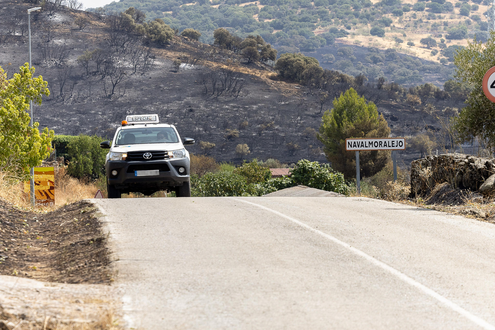 Un automóvil circula por una carretera que recorre un área calcinada por el incendio forestal originado este lunes en Navalmoralejo (Toledo) y que ha quemado 3.250 hectáreas, la mayoría en Extremadura, y ya está perimetrado al 90 %, aunque las condiciones meteorológicas son desfavorables para su control. EFE/Ismael Herrero
