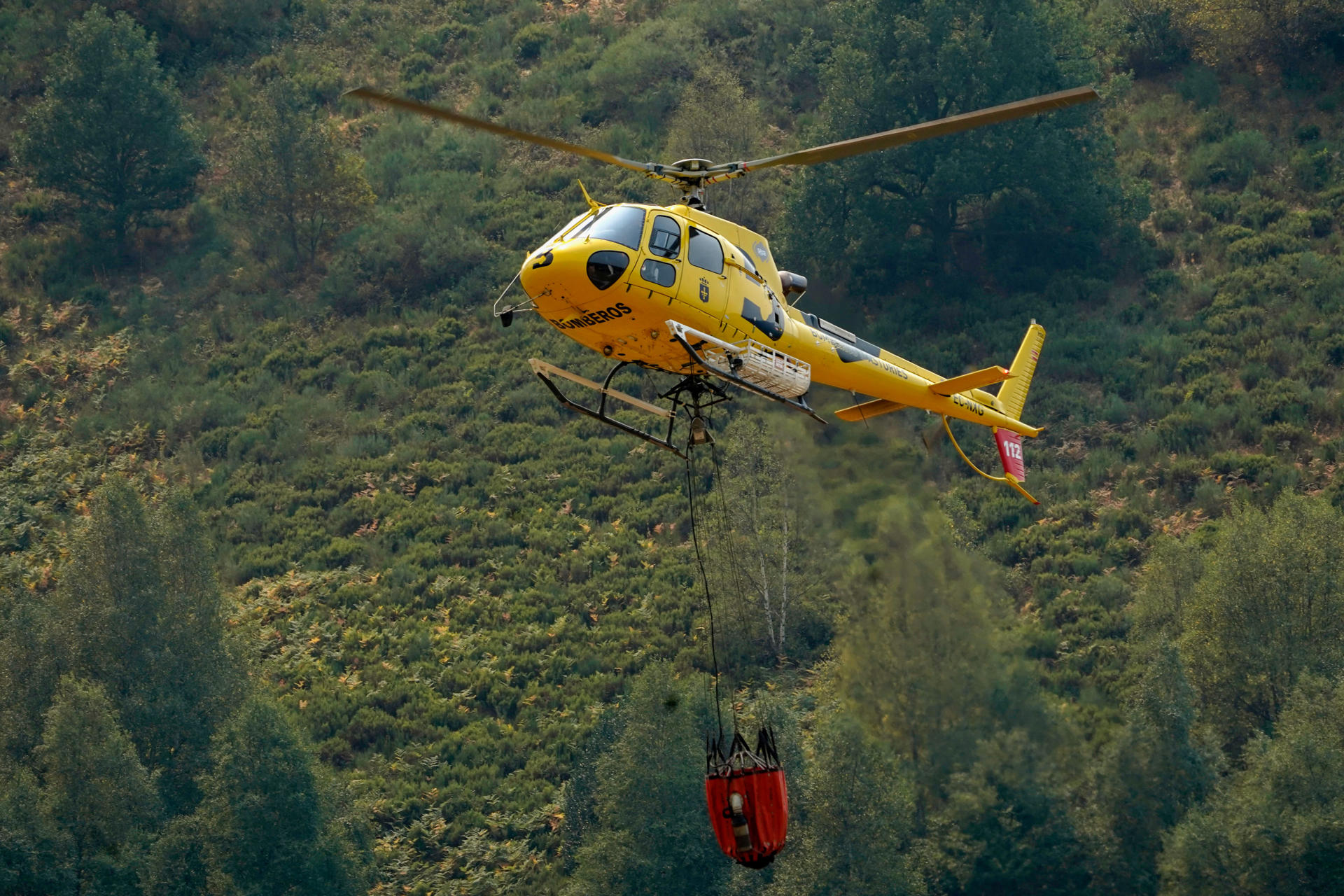 Un helicóptero tras arrojar agua al incendio este jueves, en Genestoso (Cangas del Narcea). EFE/ Paco Paredes
