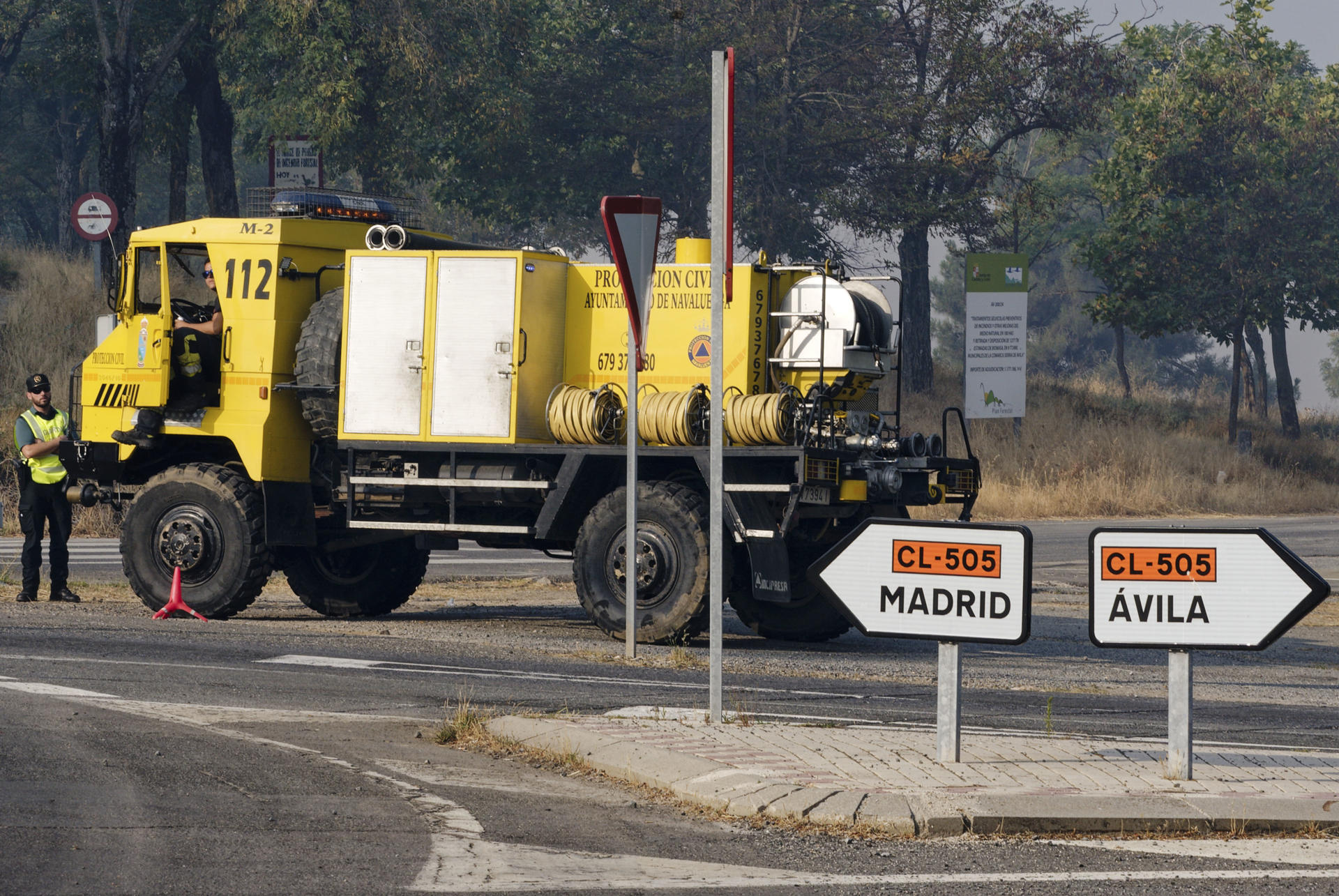 Un tramo de la carretera CL-505 cortada por el incendio que afecta a la localidad abulense de Las Navas del Marqués, un fuego que se declaró a primera hora de la tarde del viernes en el municipio abulense de San Bartolomé de Pinares y avanzó en dirección a Las Navas del Marqués, en el este de la provincia de Ávila. Los técnicos de extinción tratan de asegurar el perímetro para evitar reproducciones, ante el viento y el aumento de temperaturas que se produzca durante este sábado. EFE/ Raúl Sanchidrián