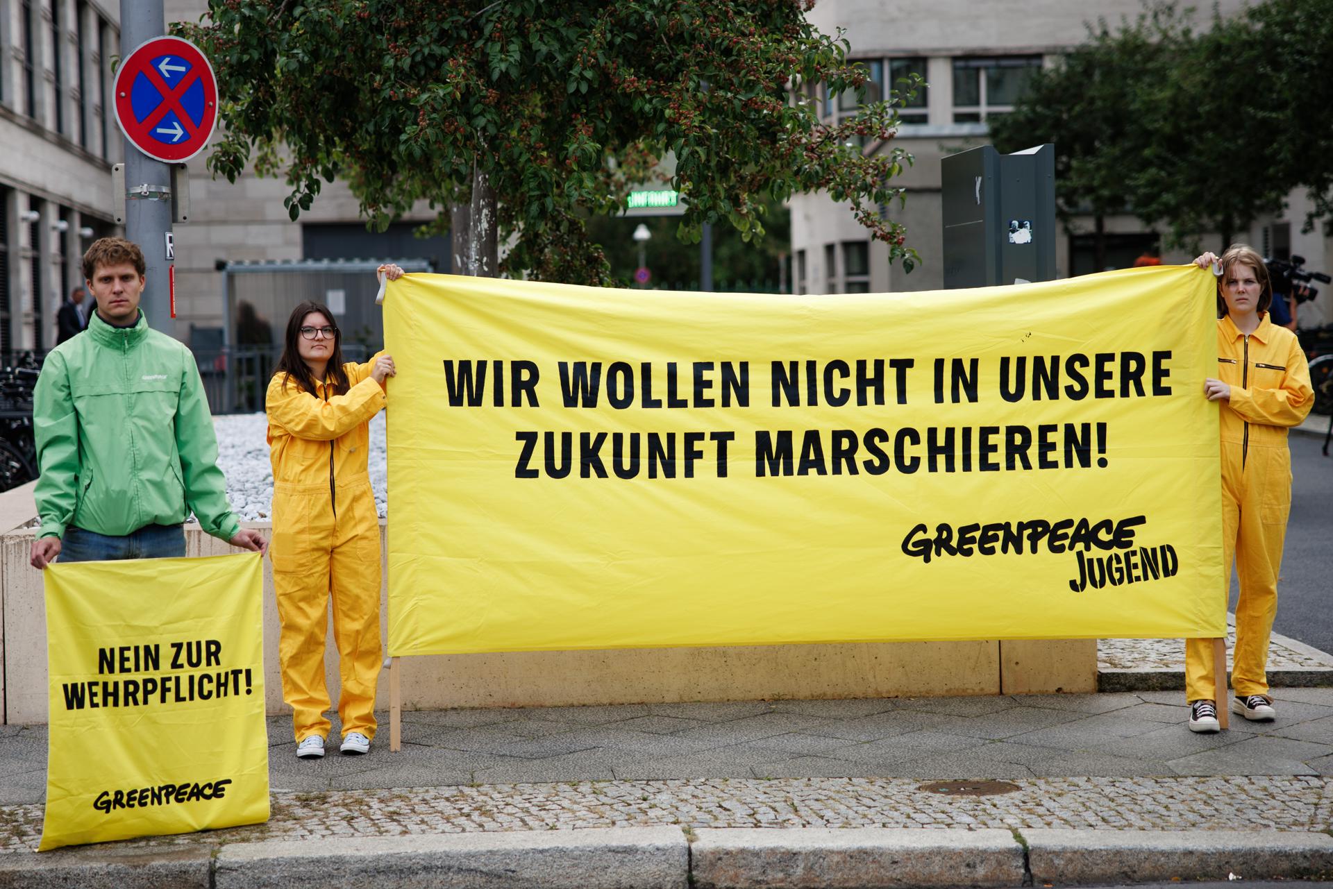 Activistas de Greenpeace sostienen una pancarta que dice '¡No queremos marchar hacia nuestro futuro!' (D) y un cartel que dice '¡No al servicio militar obligatorio!' con motivo de una reunión del gabinete alemán en el Ministerio de Defensa en Berlín, el 27 de agosto de 2025. EFE/EPA/CLEMENS BILAN