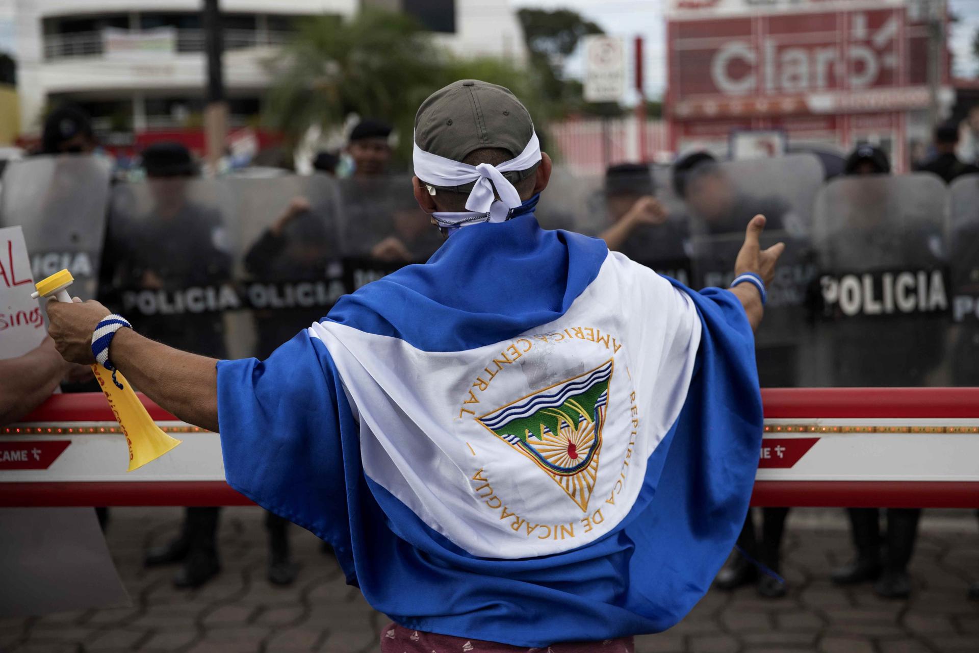Fotografía de un joven con una bandera de Nicaragua frente a Policías, en Managua (Nicaragua). EFE/Jorge Torres