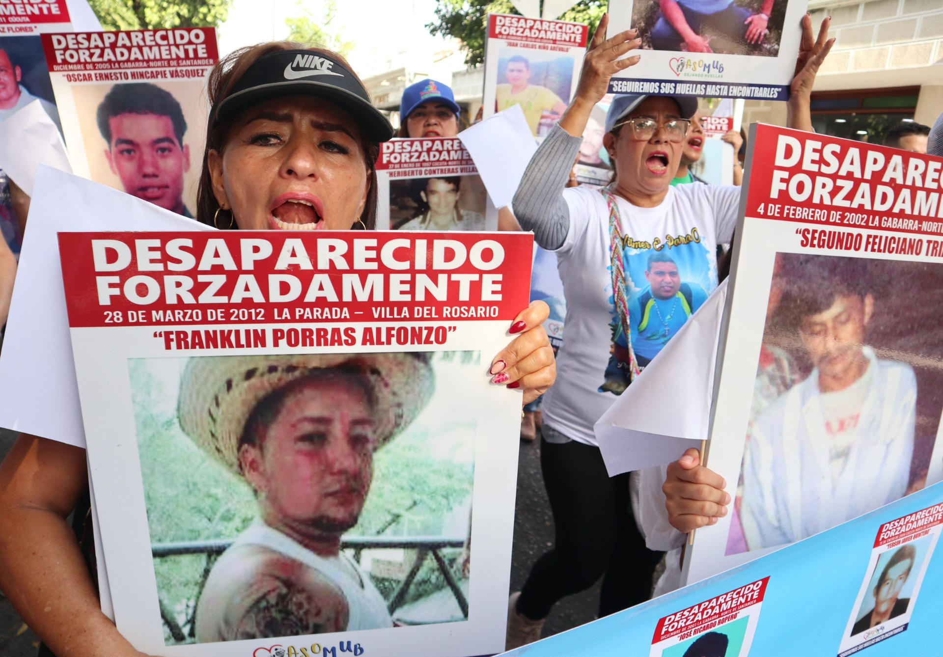 Familiares de víctimas de desaparición forzada protestan este sábado sosteniendo carteles con fotos de sus allegados desaparecidos, en Cúcuta (Colombia). EFE/Mario Caicedo
