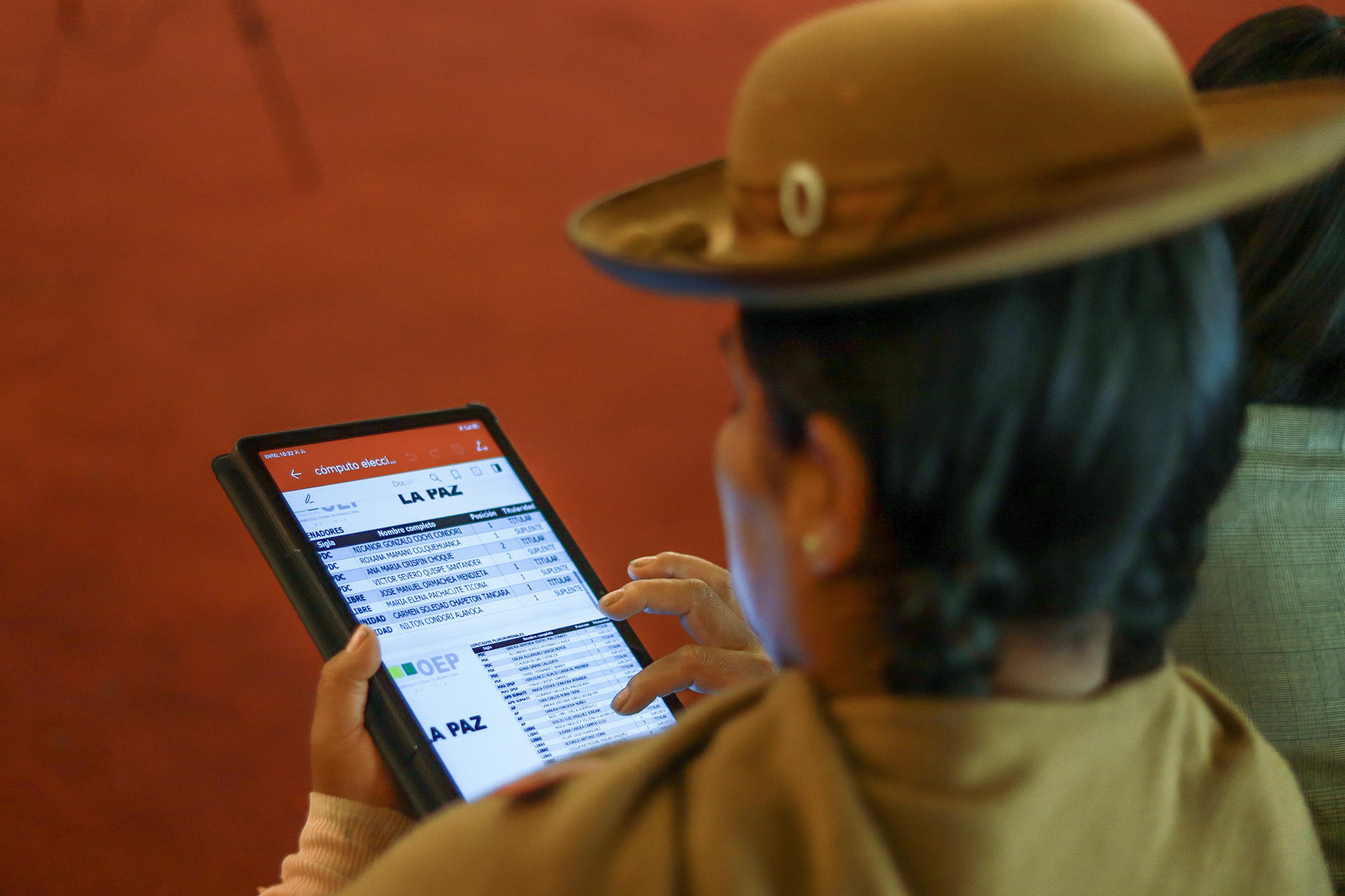 Una mujer aimara lee en un dispositivo móvil los resultados oficiales de las elecciones presidenciales a nivel nacional este martes, en La Paz (Bolivia). EFE/ Gabriel Márquez
