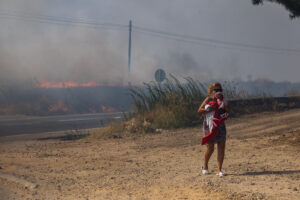 Una mujer junto al incendio que se ha declarado esta tarde entre Torrijos y Novés en la provincia de Toledo, que está afectando a una zona de rastrojos, aunque se ha extendido con rapidez debido al fuerte viento. EFE/Ismael Herrero
