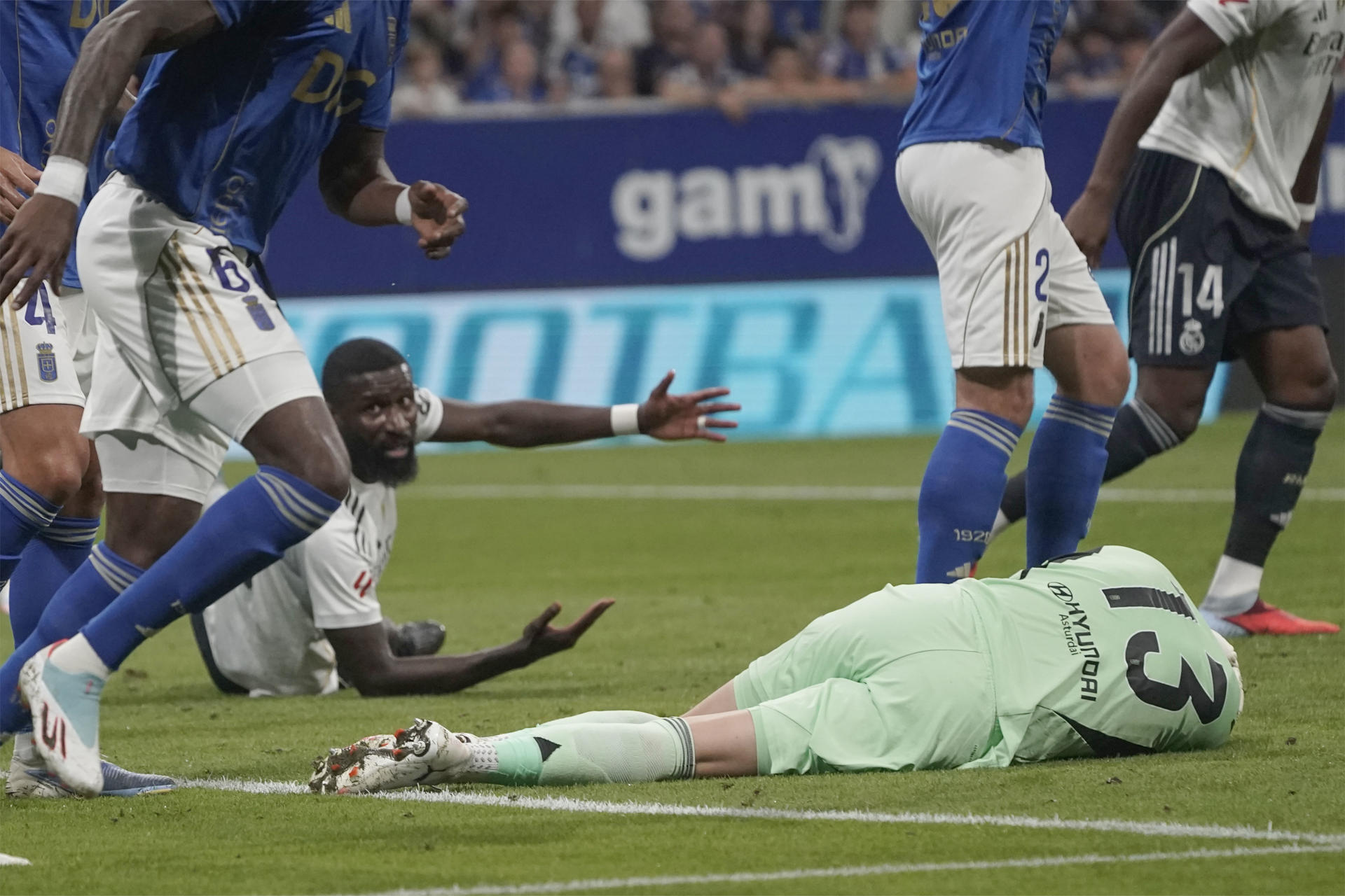 El portero del Real Oviedo Aarón Escandell (d) en el suelo durante el partido de LaLiga que enfrenta al Real Oviedo y al Real Madrid este domingo en el estadio Carlos Tartiere. EFE/Paco Paredes
