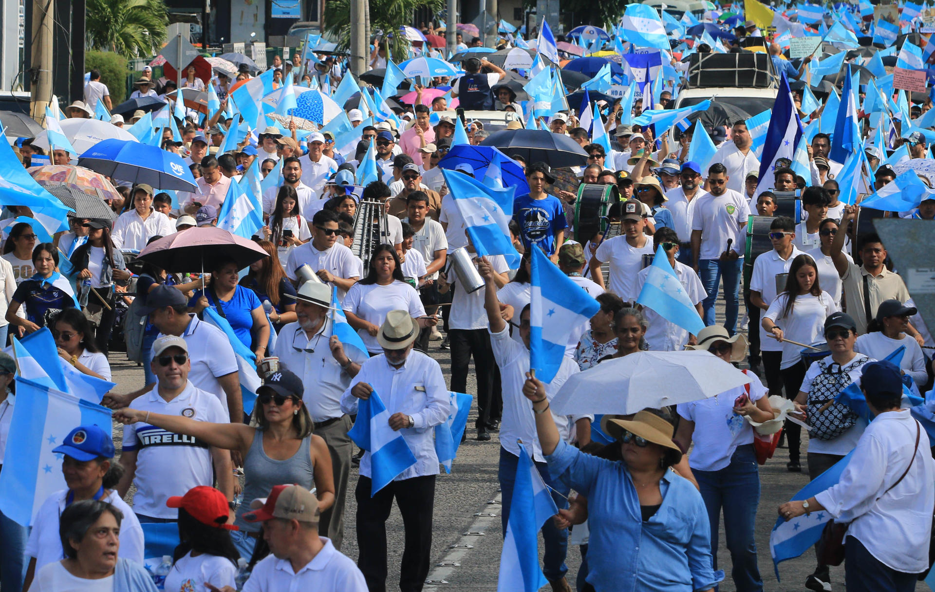 Personas sostienen banderas de Honduras durante una marcha por la paz este sábado, en San Pedro Sula (Honduras). EFE/ Jose Valle