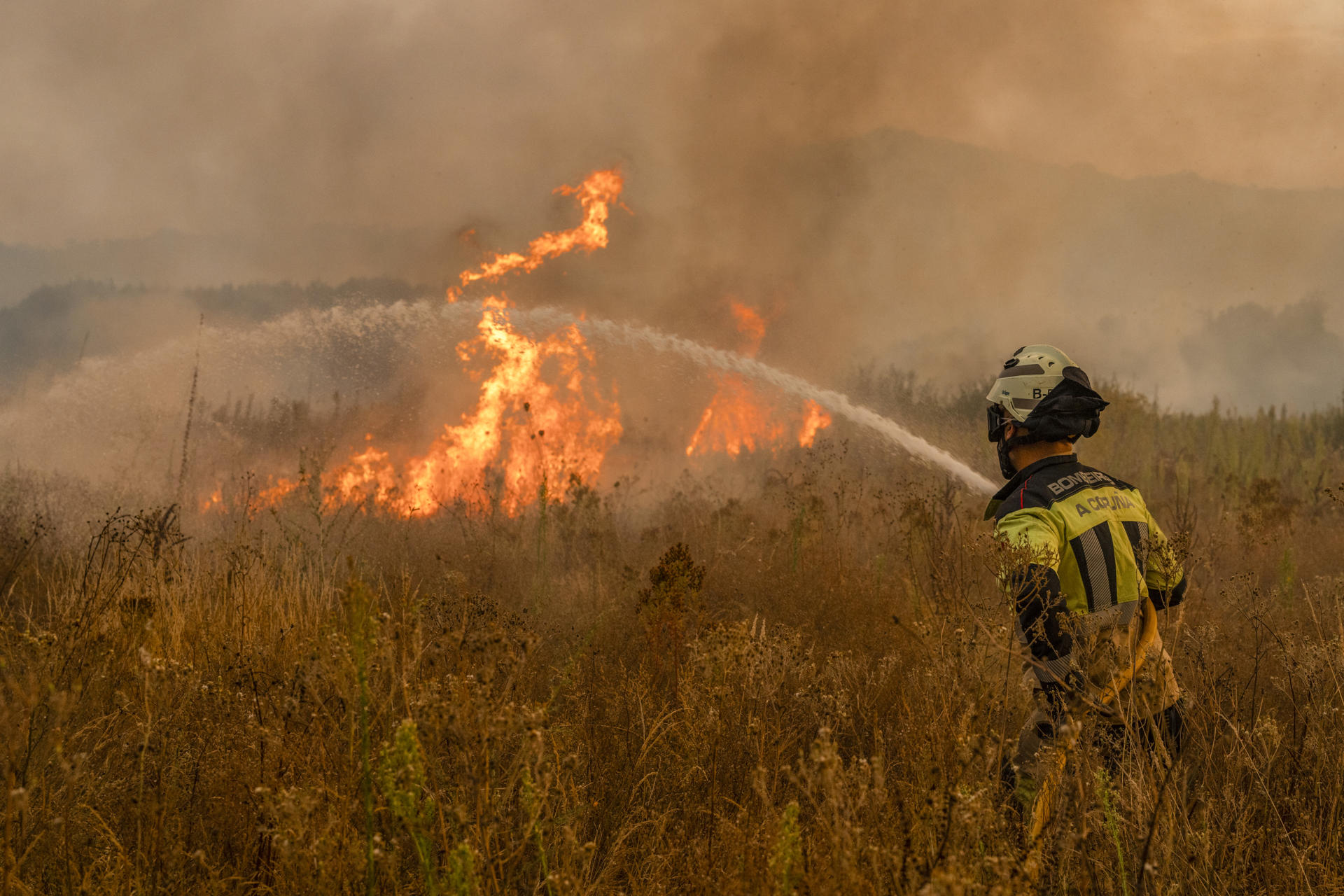 Un bombero trabaja en las labores de extinción del incendio forestal que permanece activo este martes en Monterrei (Ourense). EFE // Brais Lorenzo