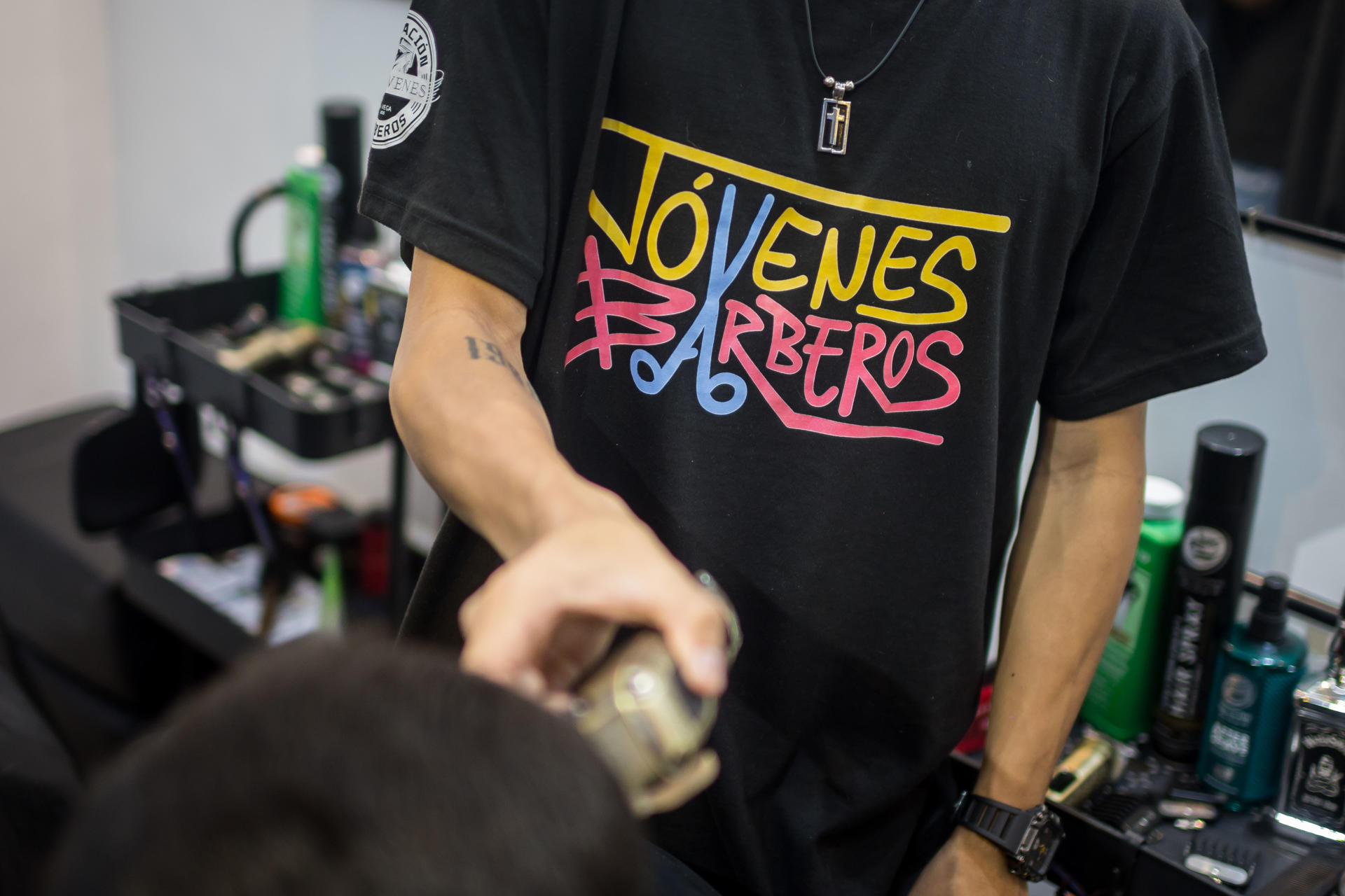 Fotografía del 28 de agosto de 2025 de una persona vistiendo la camiseta de 'Jóvenes barberos' atendiendo un cliente en una barbería, en Caracas (Venezuela). EFE/ Miguel Gutiérrez