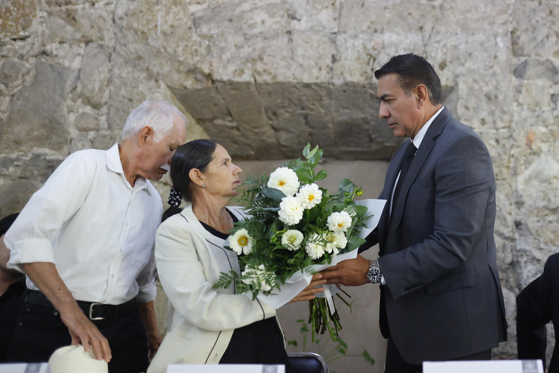 El secretario de gobierno de Jalisco, Salvador Zamora (d), ofrece un ramo de flores a María Natividad Guerrero, madre de Dalia Guadalupe Cruz, durante un evento de disculpa pública este jueves, en el Palacio de Gobierno en Guadalajara (México). EFE/ Francisco Guasco
