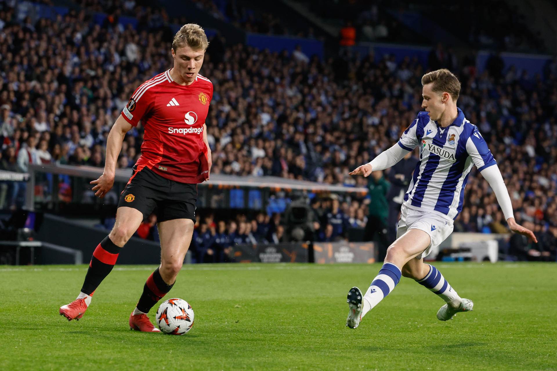 El delantero danés Rasmus Hojlund (i) ante Beñat Turrientes, durante el partido que disputó el Manchester United frente a la Real Sociedad, de octavos de final la Liga Europa, en el Real Arena de San Sebastián. EFE/ Javier Etxezarreta