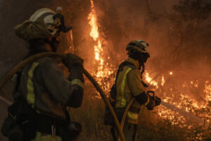 Dos bomberos durante las labores de extinción del incendio forestal que permanece activo este miércoles en As Neves (Pontevedra). EFE/ Brais Lorenzo